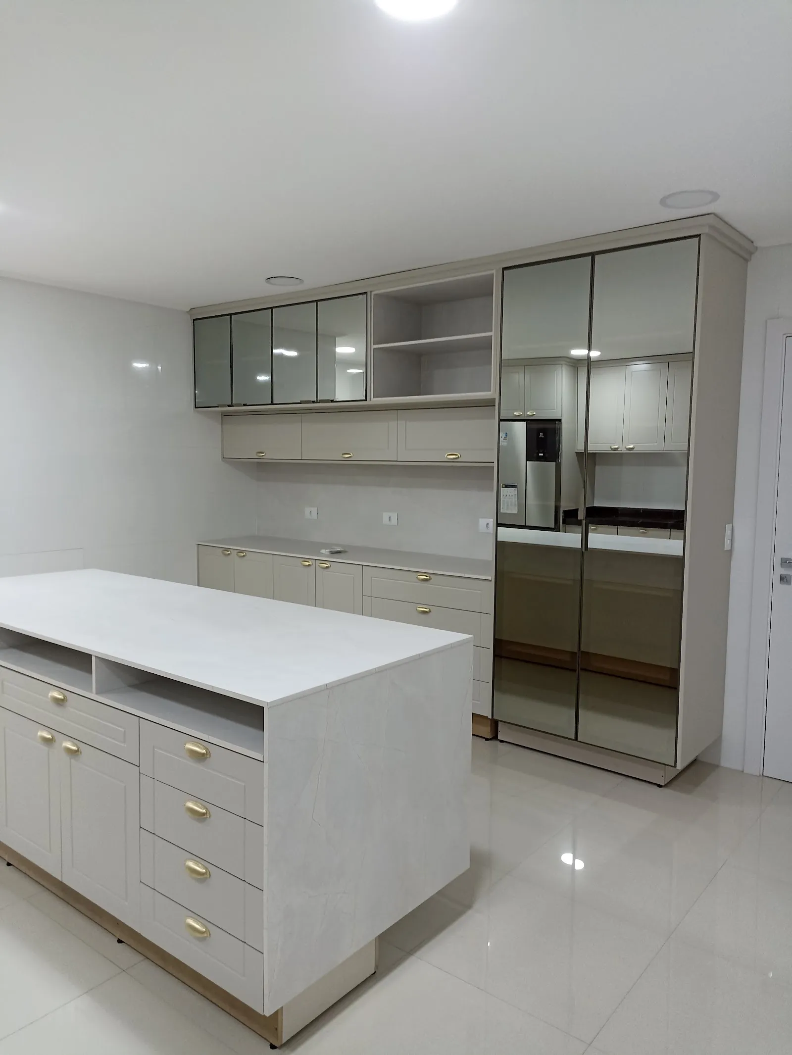 Cozinha planejada com ilha e armários com portas de vidro